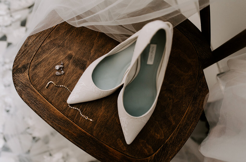 A pair of high heels and earrings, staged for wedding prep details